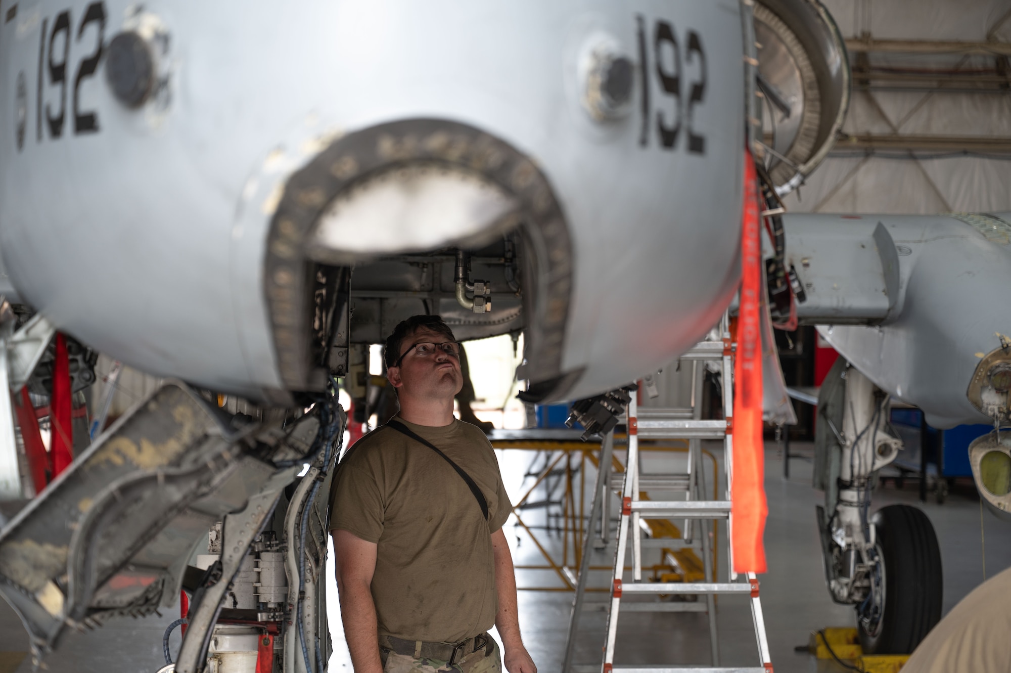 A U.S. Air Force Airman looks underneath an A-10C Thunderbolt II aircraft during phase maintenance at Davis-Monthan Air Force Base, October 23, 2025. Phase maintenance on an A-10C Thunderbolt II aircraft can take up to two weeks of around-the-clock work. (U.S. Air Force photo by Airman 1st Class Jaden Kidd)