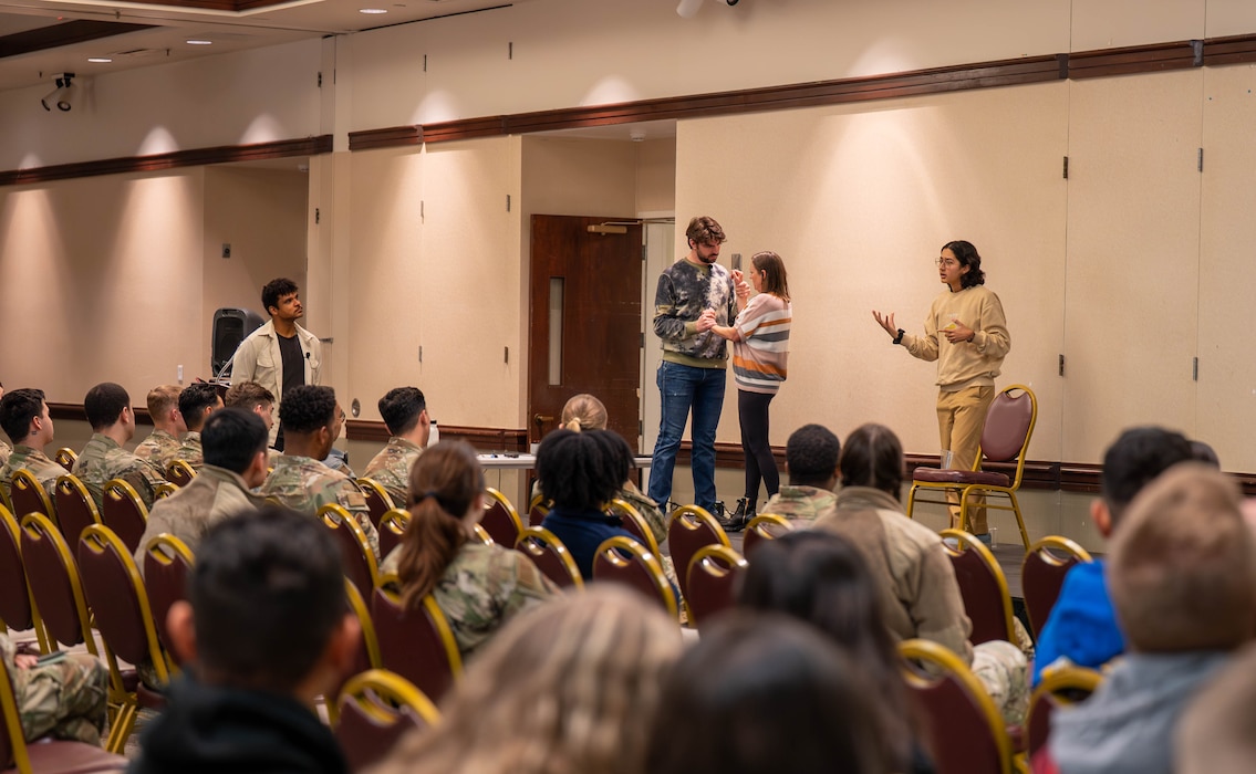 Performers act out a scene in front of Airmen