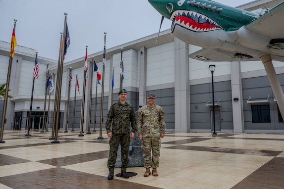 Two military men stand outside for a photo together.
