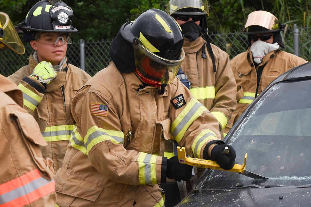 A firefighter uses a tool to break open the dashboard of a car