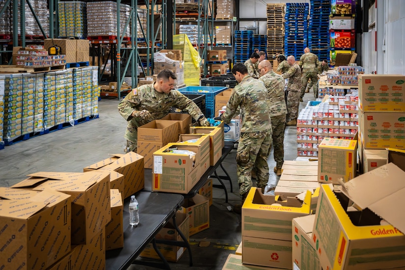 Airmen and Soldiers from the Kentucky National Guard pack hundreds of boxes with free food staples at the Dare to Care Food Bank in Louisville, Ky., Nov. 13, 2025. The boxes, containing canned fruit and vegetables, peanut butter, pasta and other nutritious foods, will be given to Kentuckians who are struggling to purchase basic groceries. (U.S. Air National Guard photos by Dale Greer)