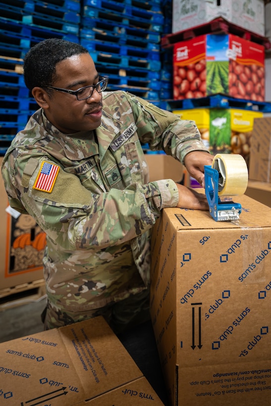 U.S. Army Staff Sgt. Christopher Martin from the Kentucky National Guard’s Joint Force Headquarters-Kentucky prepares boxes to be packed with free groceries at the Dare to Care Food Bank in Louisville, Ky., Nov. 13, 2025. The boxes, containing canned fruit and vegetables, peanut butter, pasta and other nutritious foods, will be given to Kentuckians who are struggling to purchase basic groceries. (U.S. Air National Guard photos by Dale Greer)