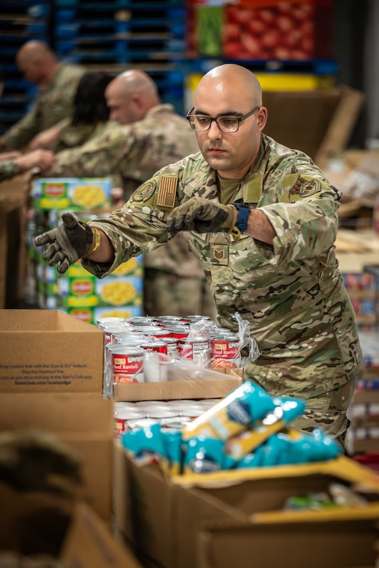 U.S. Air Force Tech. Sgt. Andrew Klosterman from the Kentucky Air National Guard’s 123rd Contingency Response Group packs boxes with free groceries at the Dare to Care Food Bank in Louisville, Ky., Nov. 13, 2025. The boxes, containing canned fruit and vegetables, peanut butter, pasta and other nutritious foods, will be given to Kentuckians who are struggling to purchase basic groceries. (U.S. Air National Guard photos by Dale Greer)
