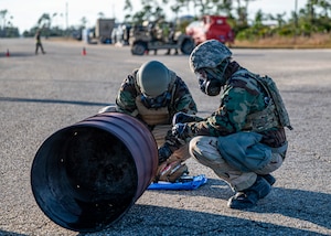 U.S. Air Force Airmen conduct a “buddy check” after donning their chemical protective gear after a simulated chemical attack during exercise Mosaic Tiger 26-1 at the Combat Support Training Range at Tyndall Air Force Base, Florida, Nov. 18, 2025. The gear protects members from most contaminants of biological, chemical and radiological threats, and the “buddy checks” aim to ensure that the gear is worn properly. (U.S. Air Force photo by Senior Airman Leonid Soubbotine)