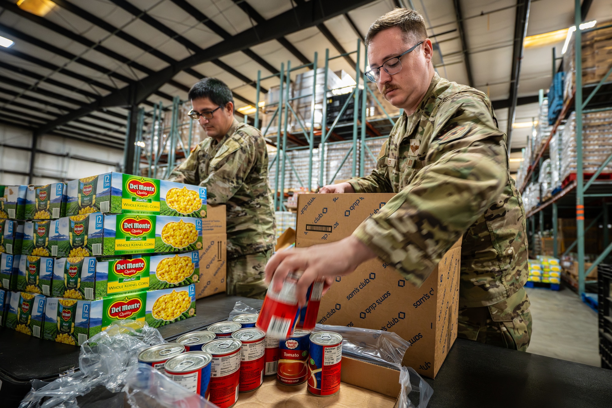 U.S. Army Staff Sgt. Brandon Tagarook, left, of the Kentucky Army National Guard’s 202nd Army Band, and U.S. Air Force Tech. Sgt. Alex Koehler of the Kentucky Air National Guard’s 123rd Contingency Response Group pack boxes with free groceries at the Dare to Care Food Bank in Louisville, Ky., Nov. 13, 2025. The boxes, containing canned fruit and vegetables, peanut butter, pasta and other nutritious foods, will be given to Kentuckians who are struggling to purchase basic groceries. (U.S. Air National Guard photos by Dale Greer)