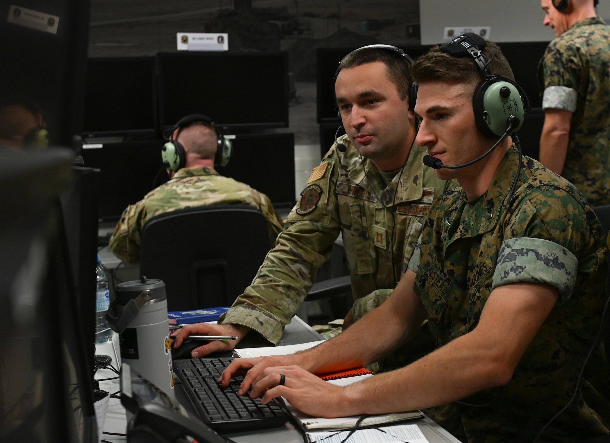 U.S. Air Force Capt. Chase Winans, 606th Air Control Squadron section lead, left, and U.S. Marine Corps 1st Lt. William Haystead, Marine Air Support Squadron 3 senior air director, right, analyze information during SPARTAN SHIELD 25-2 at Einsiedlerhof Air Station, Germany, September 25, 2025. SPARTAN SHIELD 25-2 is a U.S. Air Forces in Europe - Air Forces Africa Warfare Center constructive and virtual exercise that provides certification to the U.S. Army’s Air Defense Artillery Fire Control Officers. (U.S. Air Force photo by Capt. Benjamin Aronson) (This photo was altered for security purposes by blurring paperwork.)