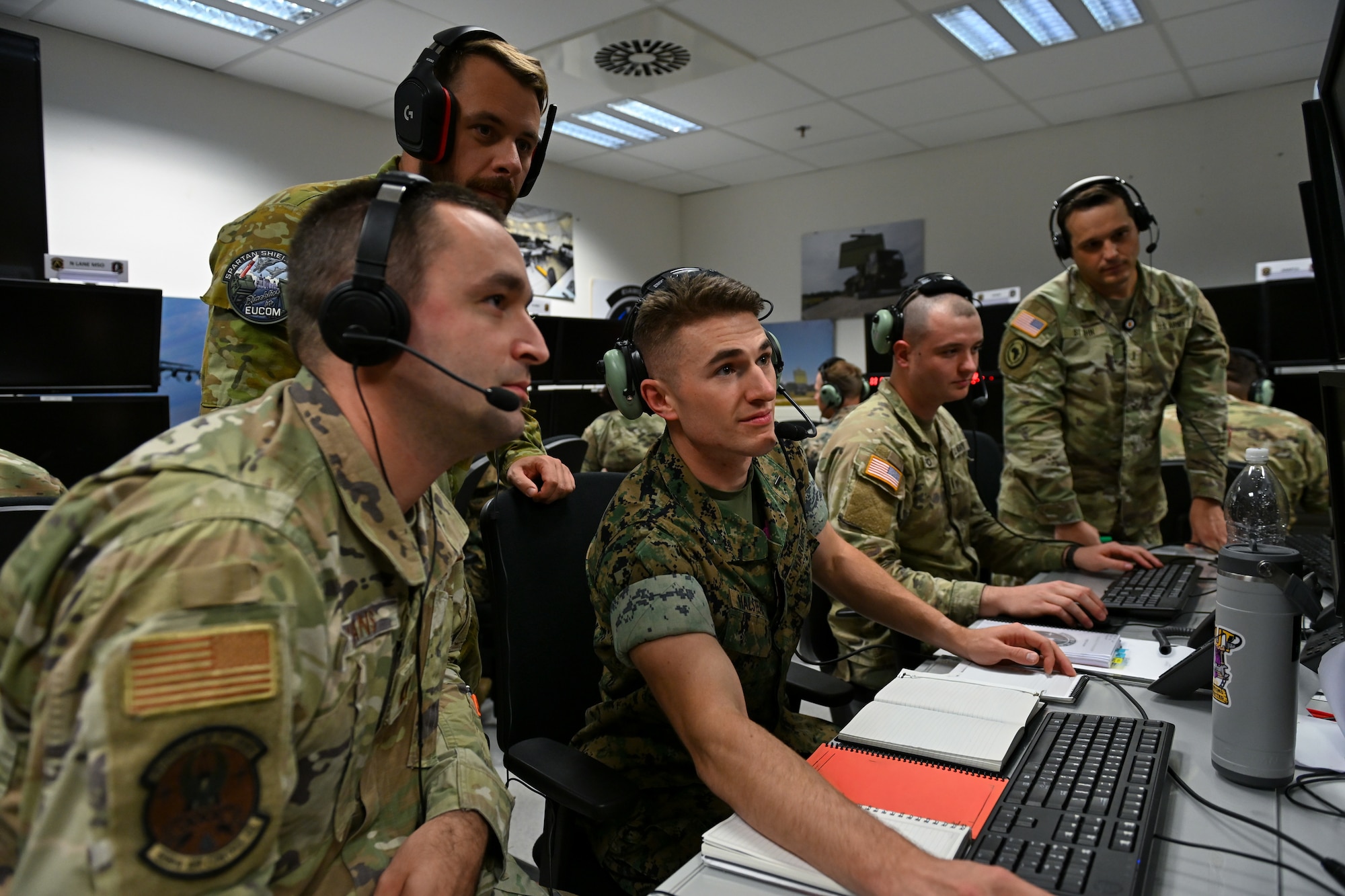 Members from the U.S. Army, U.S. Marine Corps, U.S. Air Force, and an exchange officer from the Royal Australian Air Force participate in SPARTAN SHIELD 25-2 at Einsiedlerhof Air Station, Germany, September 25, 2025. SPARTAN SHIELD 25-2 is a U.S. Air Forces in Europe - Air Forces Africa Warfare Center constructive and virtual exercise that provides certification to the U.S. Army’s Air Defense Artillery Fire Control officers. (U.S. Air Force photo by Capt. Benjamin Aronson) (This photo was altered for security purposes by blurring paperwork.)