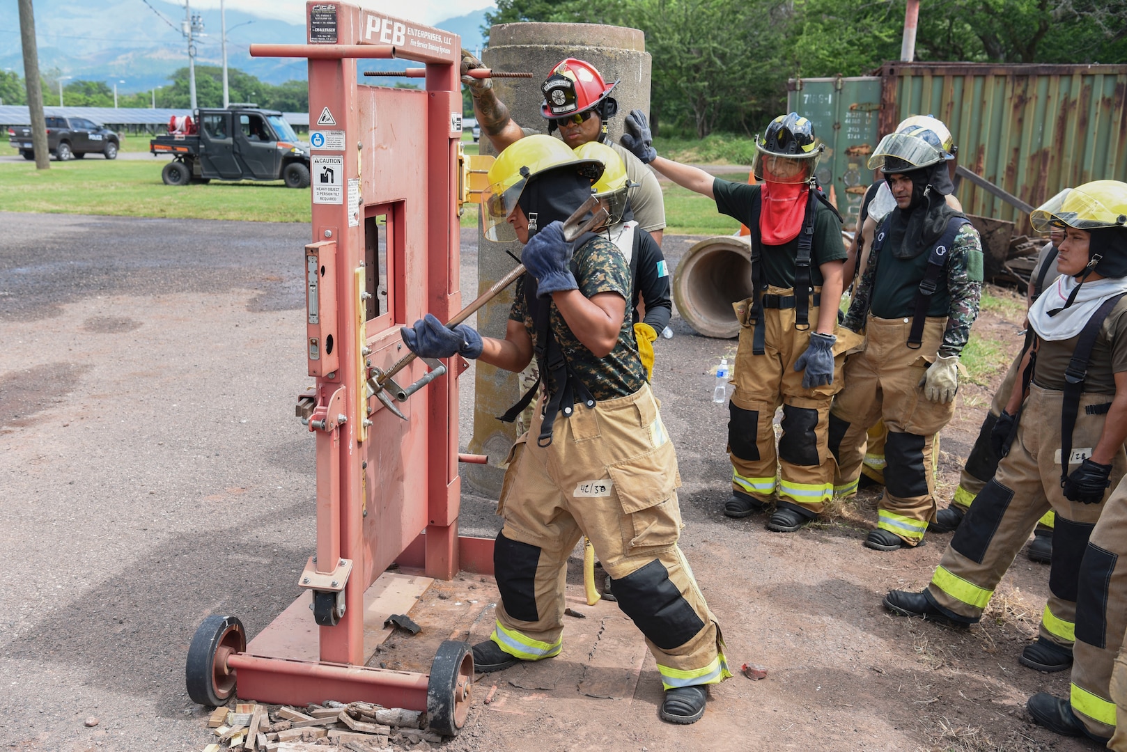 People in firefighter gear use tools to open a door