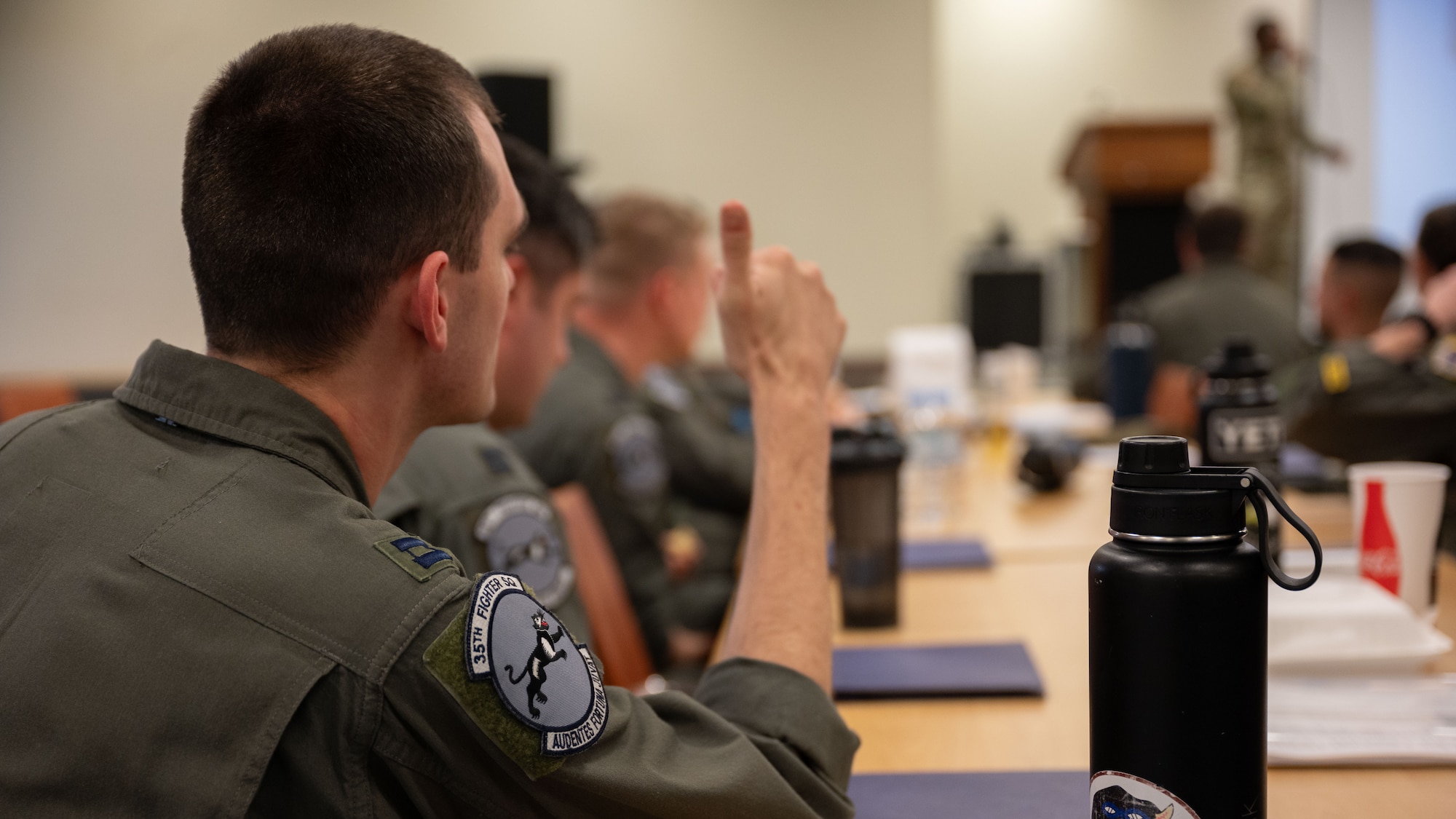 A pilot gives a thumbs up during a briefing.