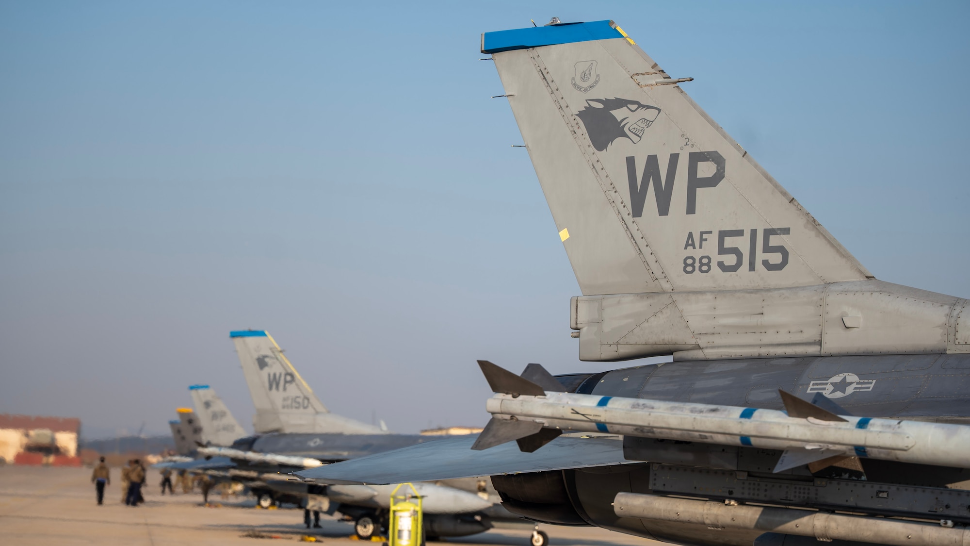 F-16 sit in a line on a taxiway after parking.