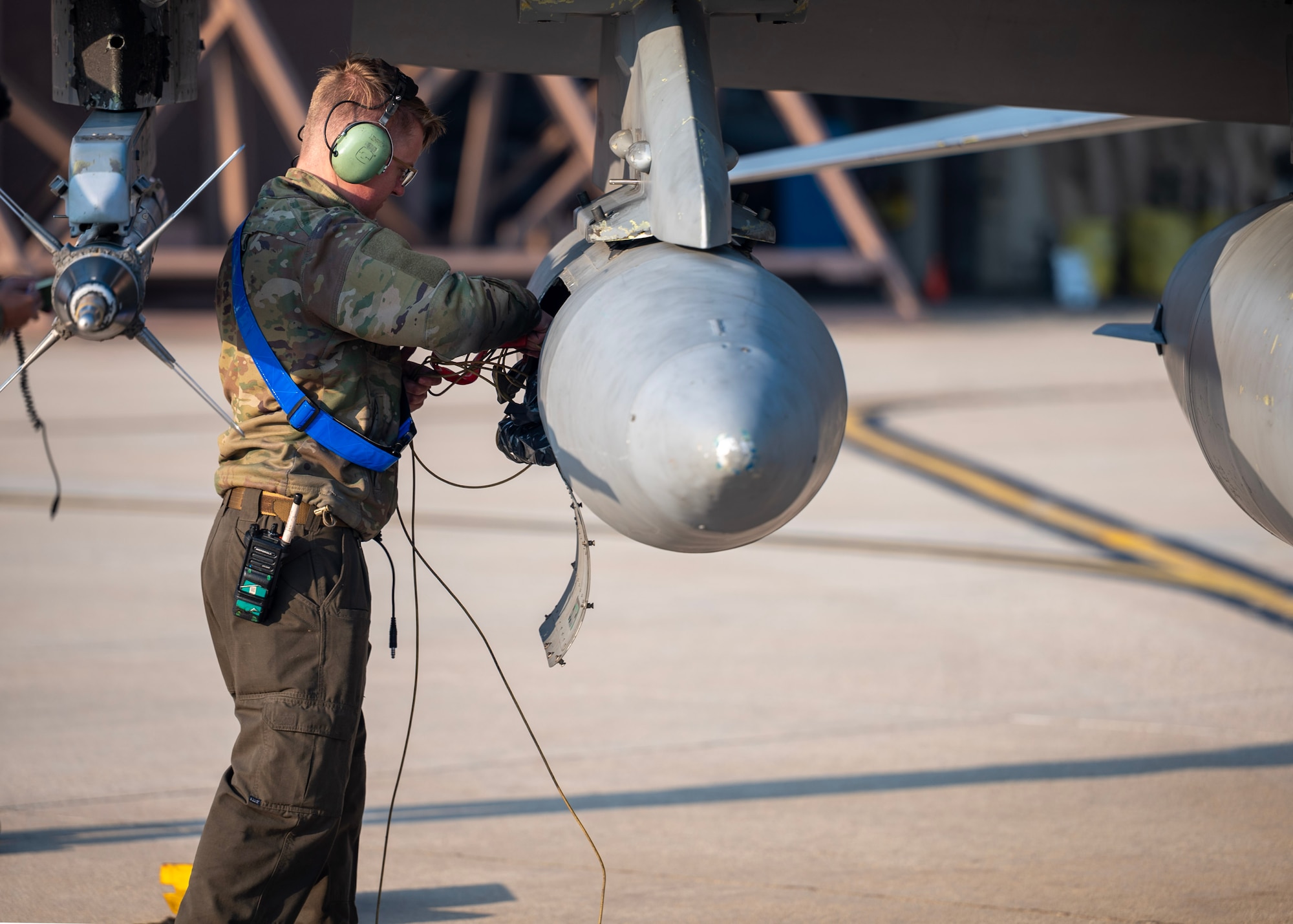 A maintainer removes equipment from anF-16's external transport pod.