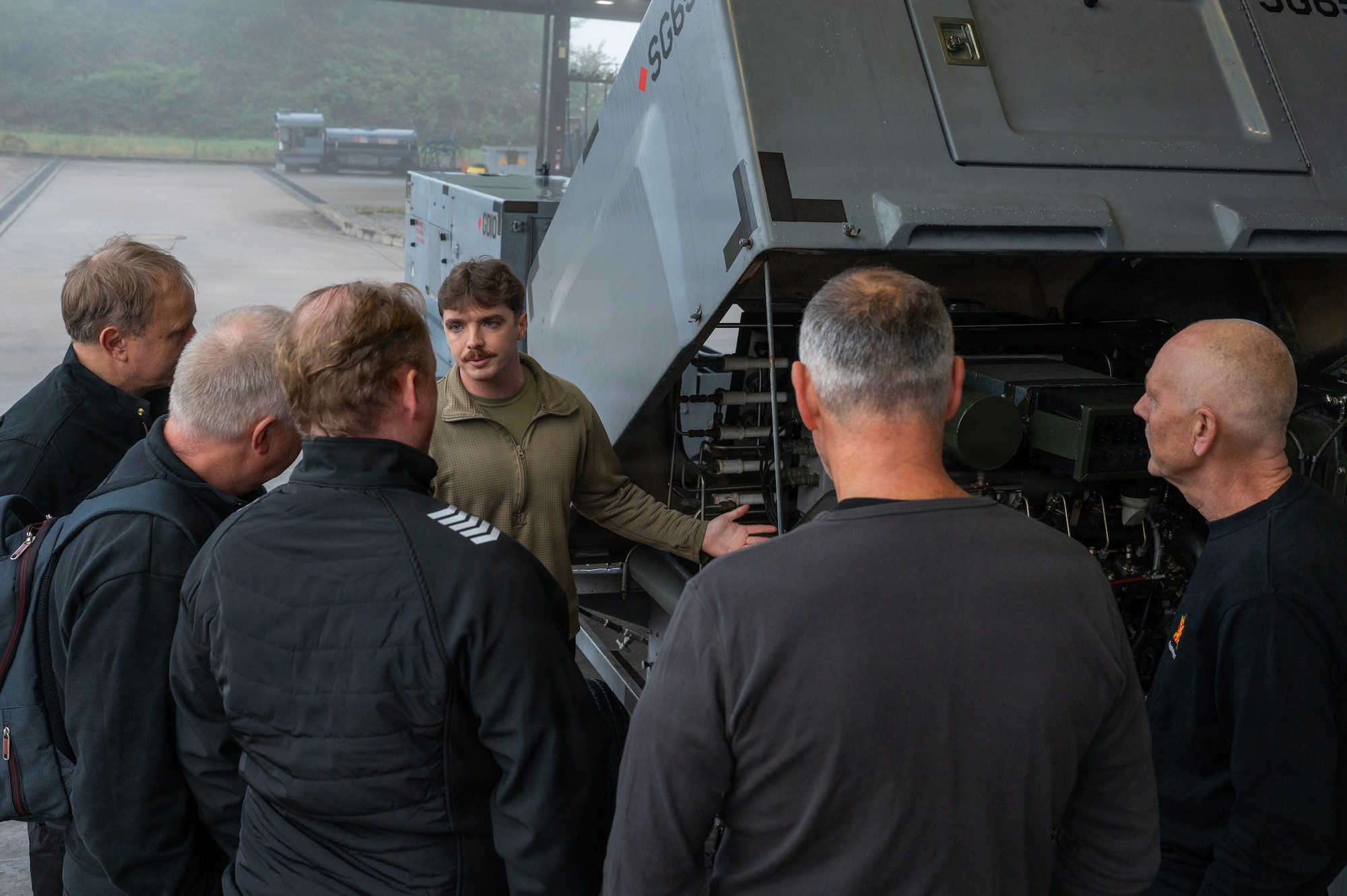 U.S. Air Force Staff Sgt. Zachary Power, 86th Maintenance Squadron noncommissioned officer in charge of dispatch, shows the inner workings of a self-generating nitrogen servicing cart to Royal Norwegian air force aerospace ground equipment service members at Ramstein Air Base, Germany, Oct. 8, 2025.