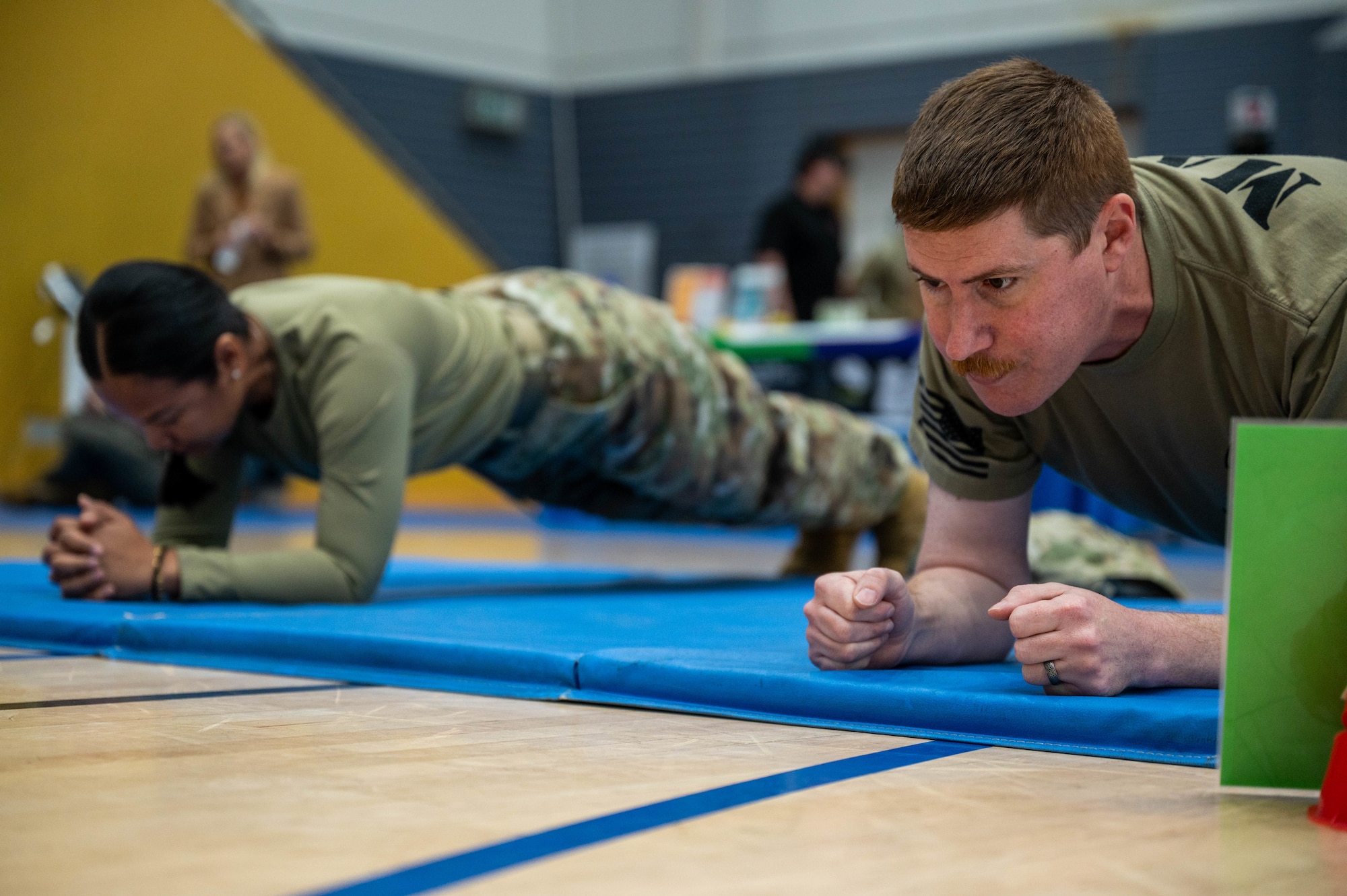 U.S. Air Force Tech. Sgts. Sida Thach and Christopher Kiebach, 1st Combat Communications Squadron Radar, Airfield, and Weather Systems technicians, plank during a physical fitness exercise during the October PT Month Health Fair at Ramstein Air Base, Germany, Oct. 17, 2025.