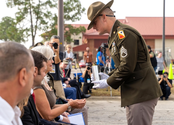A Soldier presents a ceremonial shell casing to the widow of Master Sgt. Gary Gordon
