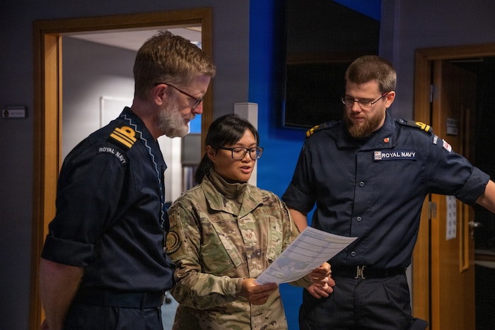Three military personnel discuss how to fill out a weather brief  form.