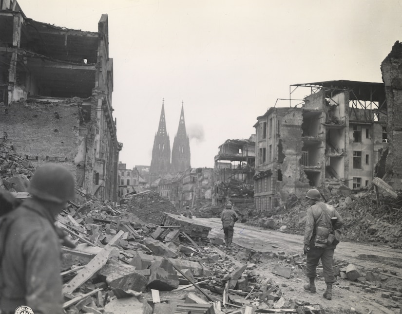 Soldiers walk past rubble in a destroyed city.