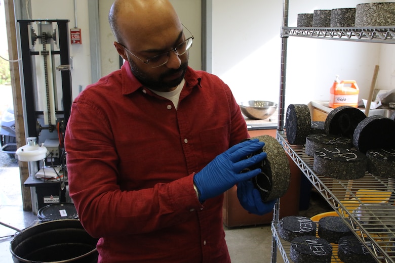 Dr. Mohamed Elshaer inspects an asphalt test core after density measurement, before the cracking test.