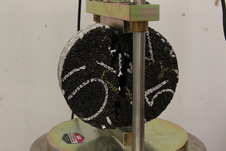 An asphalt test core undergoing a cracking test.