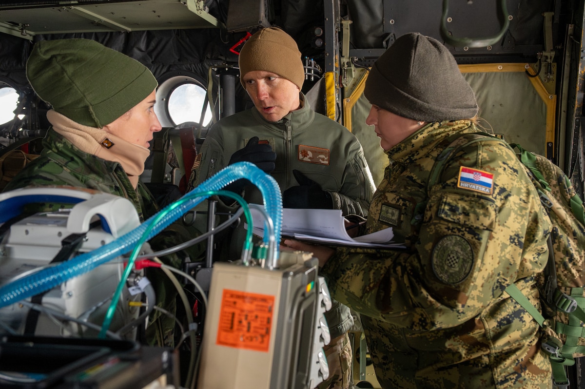 U.S. Air Force Maj. Tyson Hawkley, center, Landstuhl Regional Medical Center flight anesthesiologist, details Critical Care Air Transport Team procedures to two NATO Medical Evaluation Course students during a mock evaluation at Ramstein Air Base, Germany, Nov. 20, 2025.