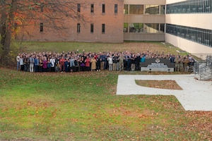 A large group of people stands outside behind the Nuclear Command, Control and Communications Integration Directorate sign
