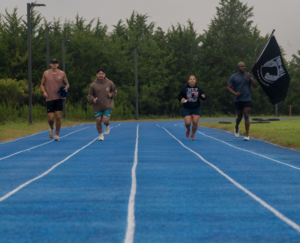Four people running on a blue track.