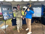 SPRINGFIELD, Mass. (Sept. 25, 2025). Navy Diver 1st Class Connor Houtchens, of Naval Submarine Medical Research Laboratory (NSMRL), poses with a Big E fair attendee during the Hartford/Springfield Navy Week event. NSMRL, part of Navy Medicine Research & Development and based out of Groton, Connecticut, sustains the readiness and superiority of U.S. undersea warfighters through innovative health and performance research and works to lead the world in delivering science solutions to ensure undersea warrior dominance. For 250 years, Navy Medicine, represented by more than 44,000 highly-trained military and civilian healthcare professionals, has delivered quality healthcare and enduring expeditionary medical support to the warfighter on, below, and above the sea and ashore. (U.S. Navy photo by Emily Swedlund /Released)
