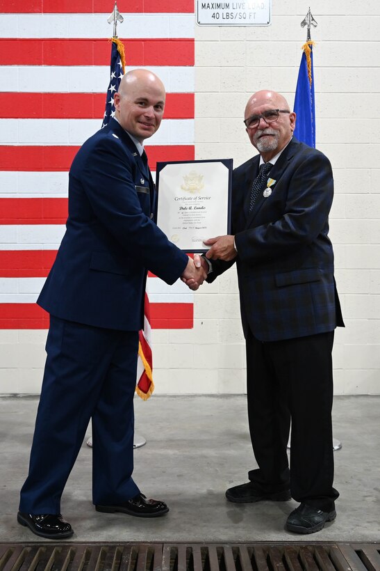 U.S. Air Force Lt. Col. Daniel Moritz, 28th Logistics Readiness Squadron commander, presents Dale Landis, 28th LRS vehicle management flight chief and fleet manager, with the certificate of service at Ellsworth Air Force Base, S.D., July 24, 2025.