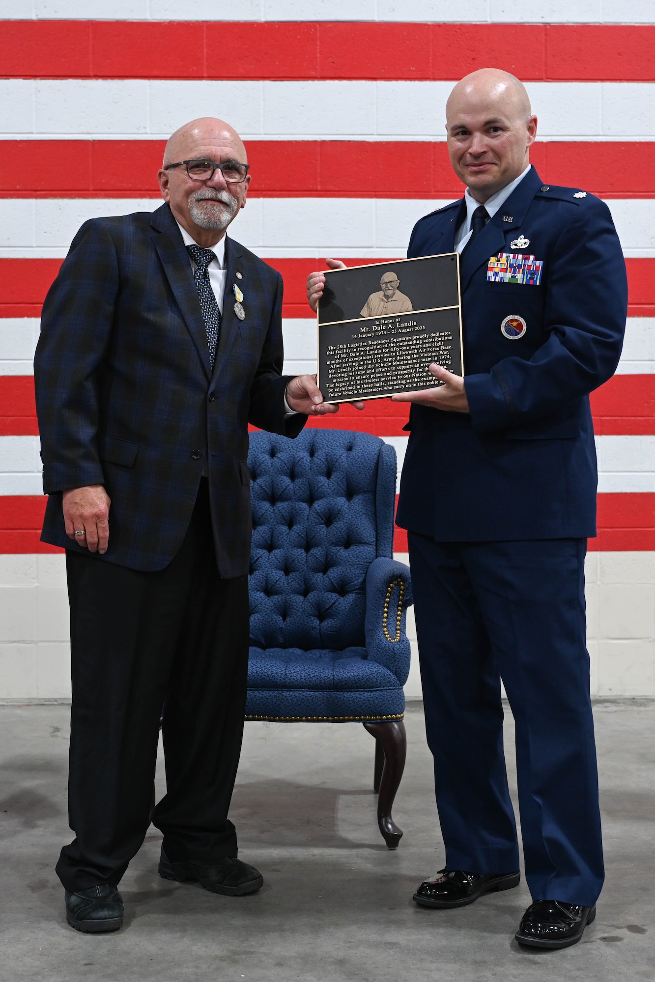 U.S. Air Force Lt. Col. Daniel Moritz, 28th Logistics Readiness Squadron commander, presents Dale Landis, 28th LRS vehicle management flight chief and fleet manager, with a plaque of dedication at Ellsworth Air Force Base, S.D., July 24, 2025.