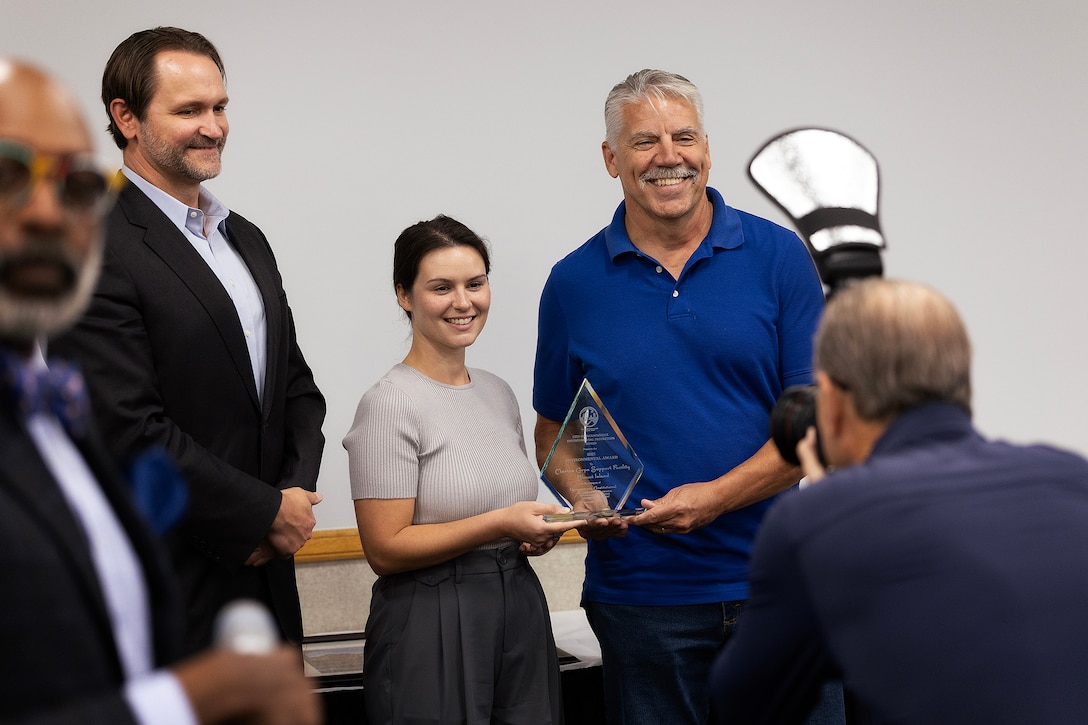 Clint Noble, Jacksonville Environmental Protection Board member, poses for photos with Taylor Comstock, environmental protection specialist at Marine Corps Support Facility Blount Island, and Shannon Easdale, environmental manager, after presenting the Government and Institutional Achievement Award during the Environmental Achievement Awards luncheon Nov. 21, 2025, at the University of North Florida’s Adam W. Herbert University Center in Jacksonville, Florida. (Official Marine Corps photo by Dustin Senger)
