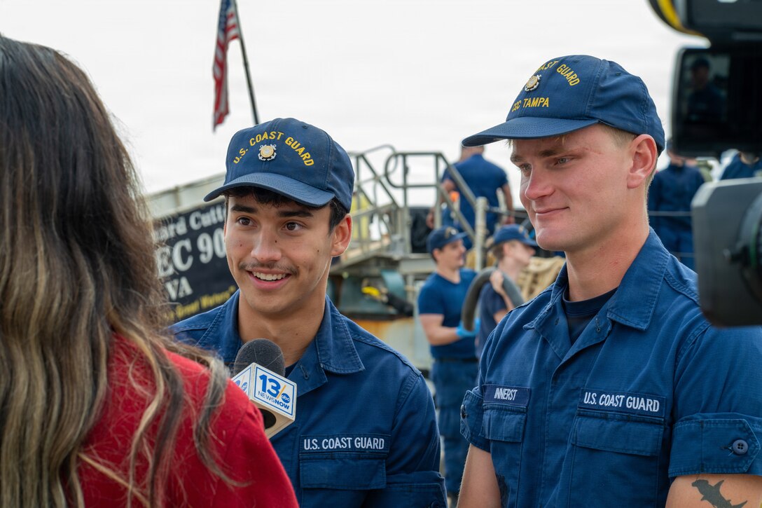 Coast Guard Seaman Joshua Lopez and Seaman Carter Innerst, crewmembers assigned to Coast Guard Cutter Tampa (WMEC 902), give an interview as the cutter returns to its homeport in Portsmouth, Virginia, on Nov. 21, 2025. Tampa’s crew deployed in support of counterdrug operations in the Eastern Pacific. (U.S. Coast Guard photo by Petty Officer 3rd Class Mason Svitenko)