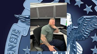 Man poses for photo at his desk.