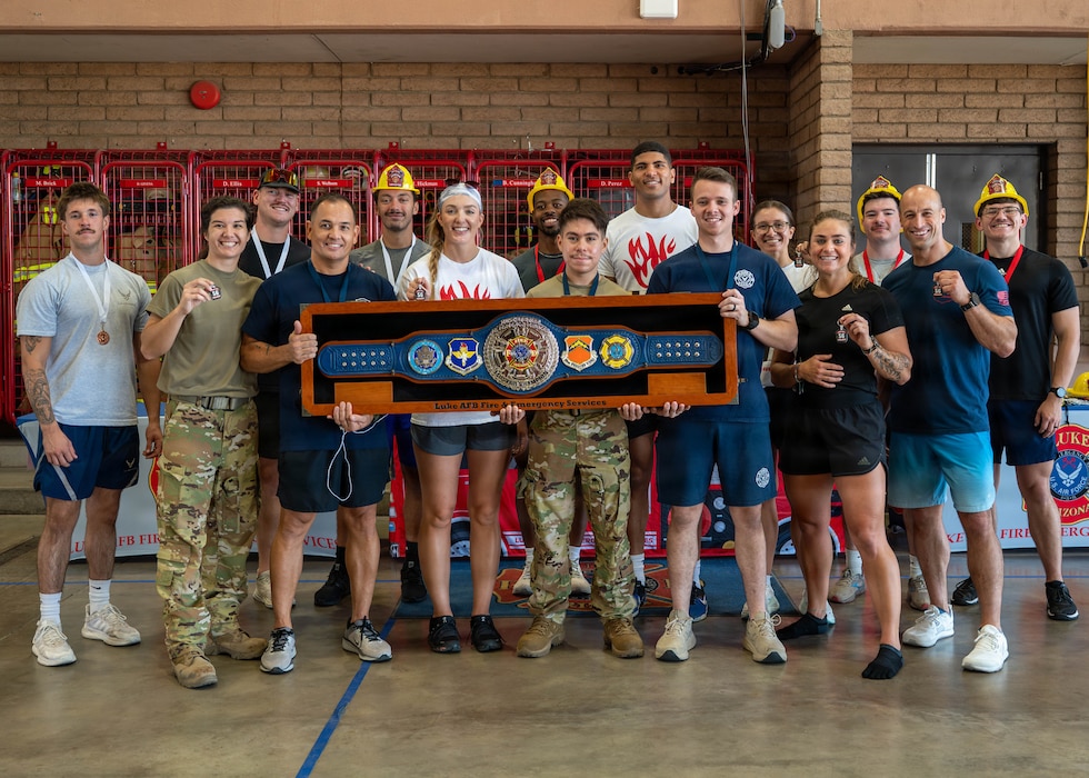 Luke Airmen pose with the championship belt after completing the firefighter challenge, Oct. 7, 2025, at Luke Air Force Base, Arizona. The event brought together Airmen and firefighters to promote camaraderie and fire safety awareness. Fire Prevention Week supports Luke’s commitment to a safe, mission-ready community.