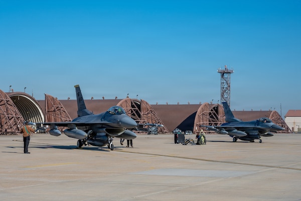 Two F-16s are parked on a taxiway.