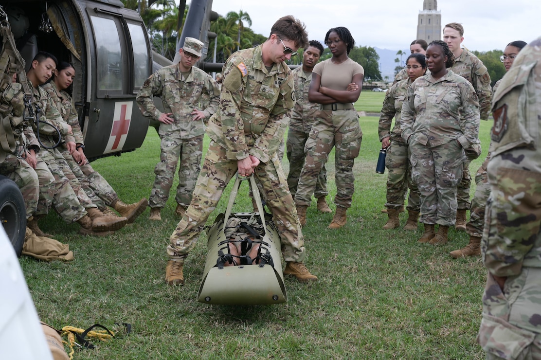 A soldier teaching Airmen on medical evacuation equipment use.