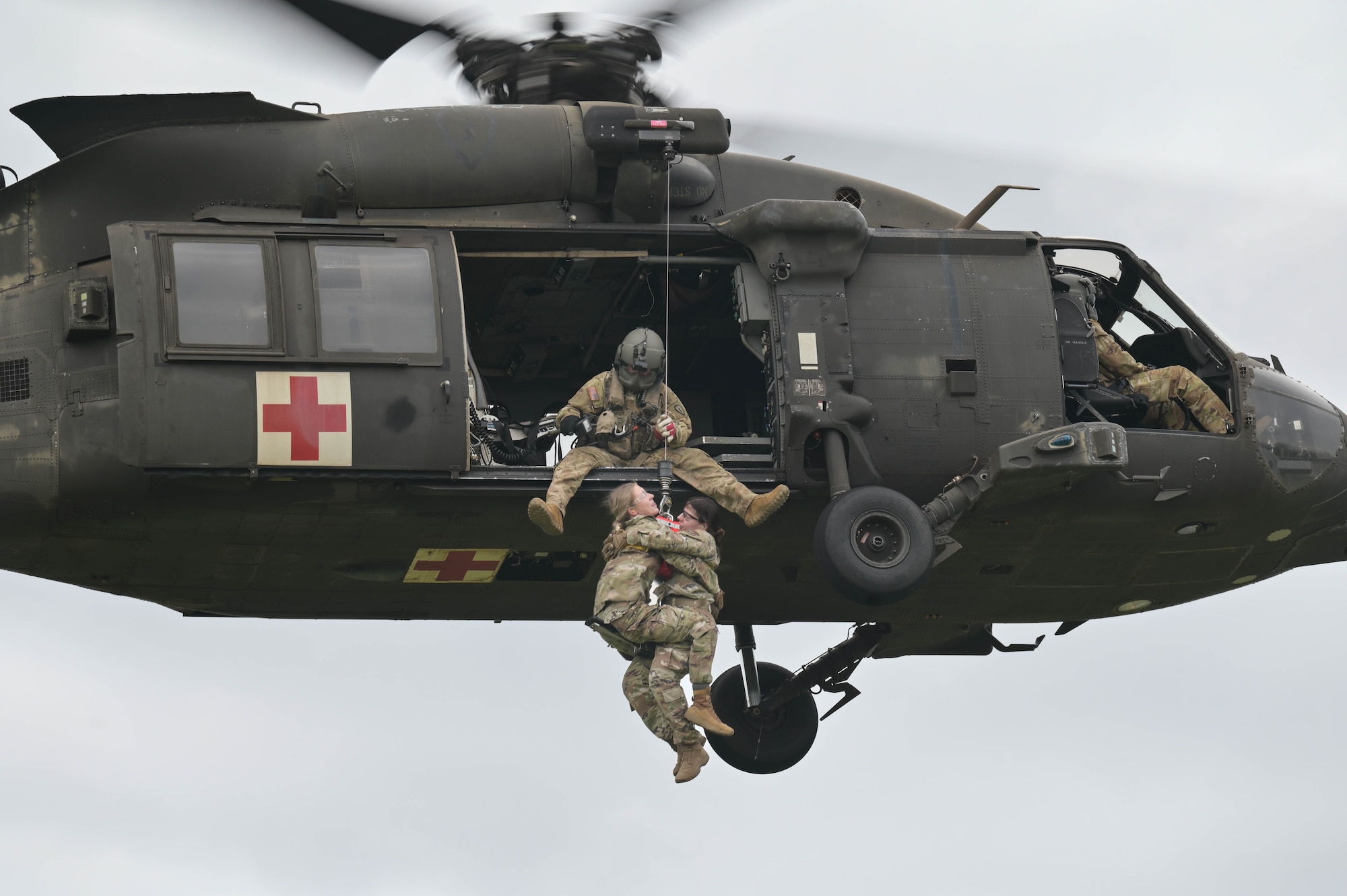 Airmen being lifted into a helicopter.