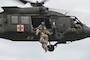 Airmen being lifted into a helicopter.