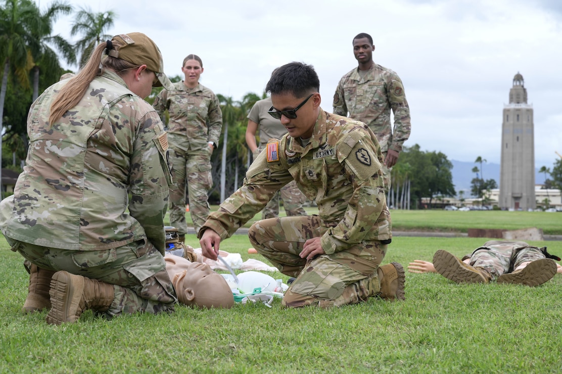 Soldier teaching medical skills to Airmen on a field.