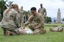 Soldier teaching medical skills to Airmen on a field.