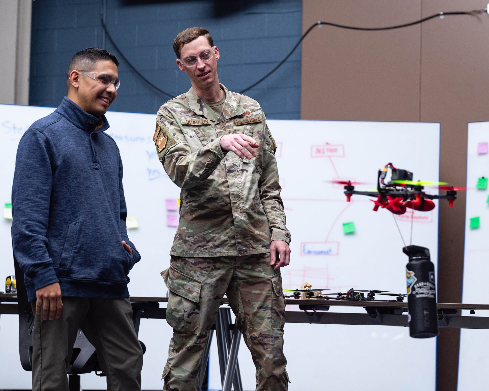 U.S. Air Force Tech. Sgt. Sean Deuerlein, 56th Fighter Wing Fighter Country Innovation section chief, and U.S. Air Force Tech. Sgt. Michael Alaniz, converse about a small unmanned aircraft system, Nov. 21, 2025, at Luke Air Force Base, Arizona.