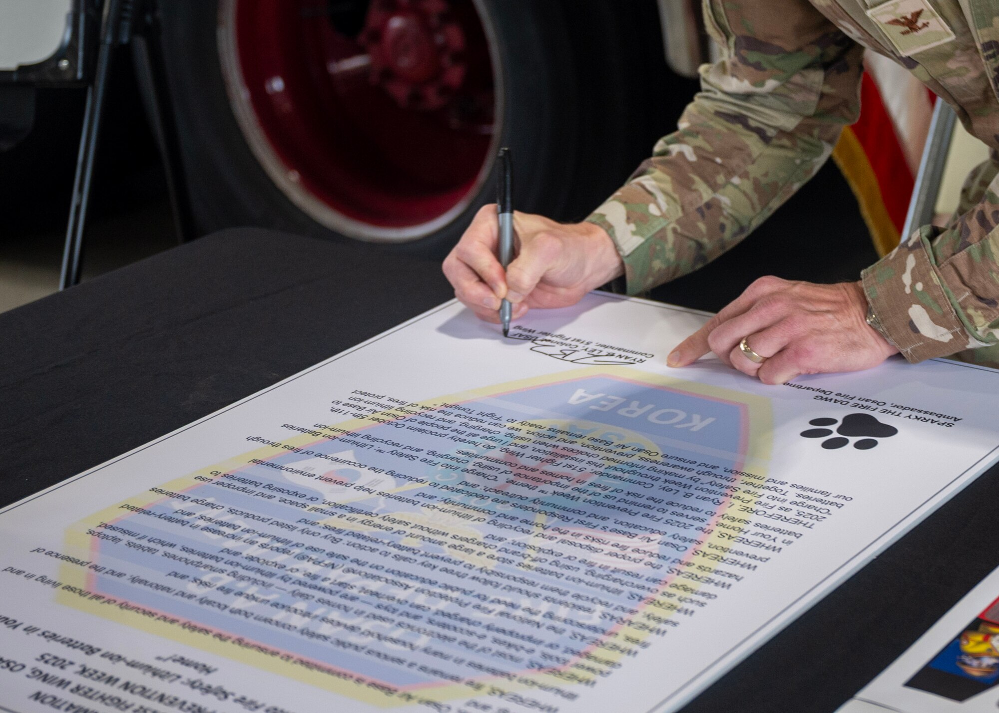 U.S. Air Force Col. Ryan Ley, 51st Fighter Wing commander, signs a proclamation to kickstart Fire Prevention Week at Osan Air Base, Republic of Korea, Oct. 6, 2025. This year’s Fire Prevention Week theme was “Charge into Fire Safety: Lithium-ion Batteries in Your Home”, serving as a reminder that fires can start from something as small as a battery. (U.S. Air Force photos by Staff Sgt. Sarah Williams)