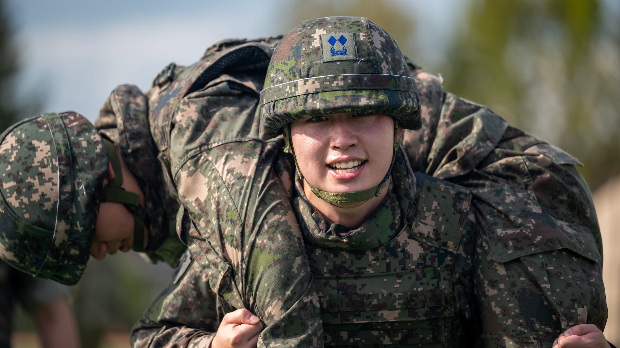 Republic of Korea Air Force Lt. Nam Kang Hee, ROKAF military police, performs a fireman carry at Osan Air Base, ROK, Oct. 23, 2025. Airmen were required to execute buddy drags across 100 yards, reinforcing life-saving casualty evacuation skills under physical stress. (U.S. Air Force photo by Staff Sgt. Sarah Williams)