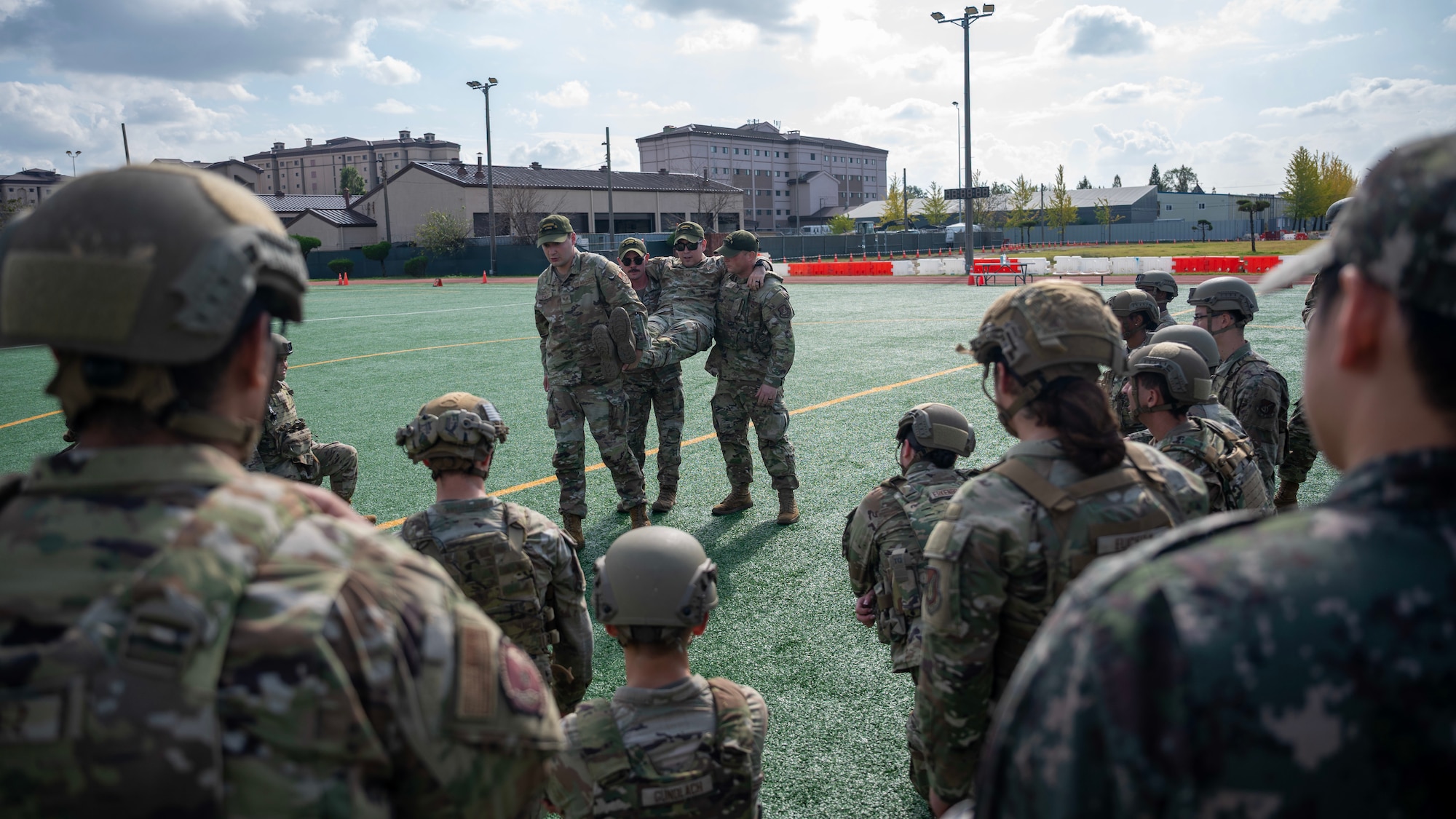 Members of the 51st Security Forces Squadron demonstrate a three-person carry during a Combat Readiness Course at Osan Air Base, Republic of Korea, Oct. 23, 2025. Airmen were required to execute buddy drags across 100 yards, reinforcing life-saving casualty evacuation skills under physical stress. (U.S. Air Force photo by Staff Sgt. Sarah Williams)
