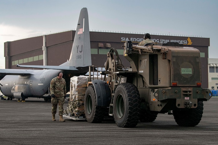 Airmen prepare to load palletized family food packs onto a C-130J Super Hercules assigned to the 36th Airlift Squadron during a foreign disaster relief operation.