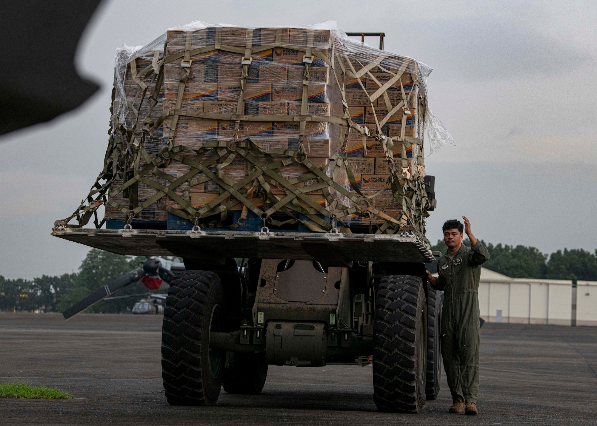 An Airman guides a 10k All-Terrain forklift transporting palletized family food packs onto a C-130J Super Hercules assigned to the 36th AS during a foreign disaster relief operation.