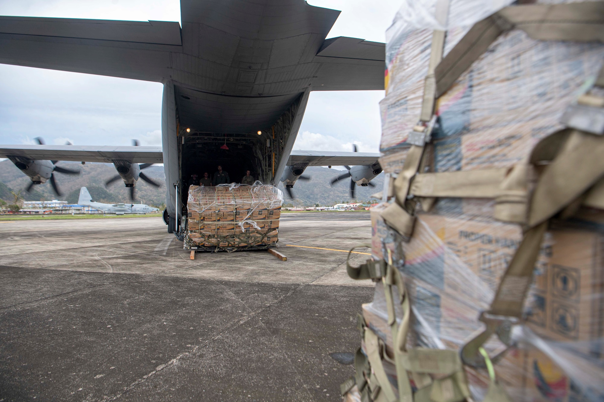 A U.S. Air Force C-130J Super Hercules assigned to the 36th Airlift Squadron, conduct a combat offload of palletized family food packs during a foreign disaster relief operation.