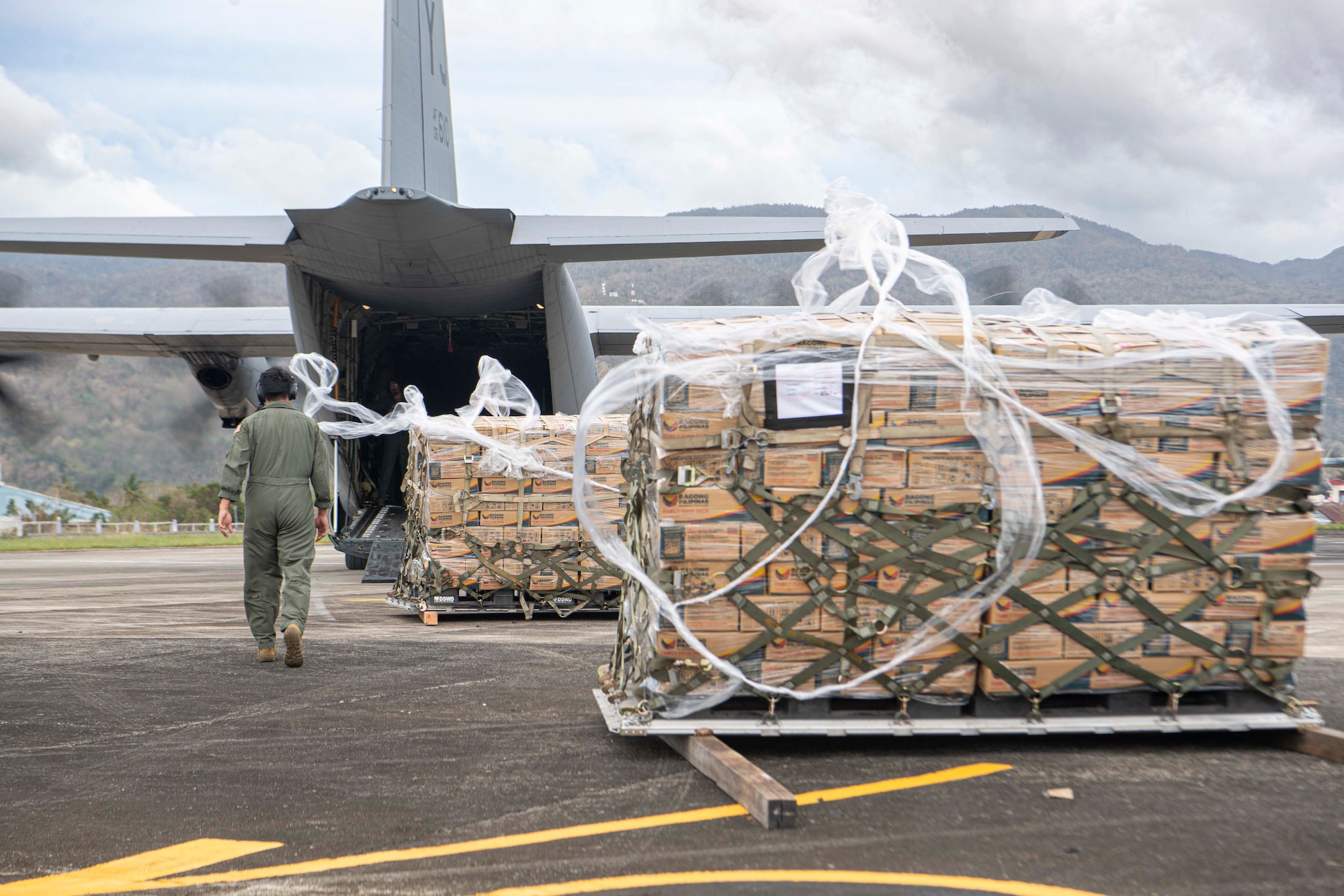 An Airman inspects palletized family food packs being offloaded during a foreign disaster relief operation.