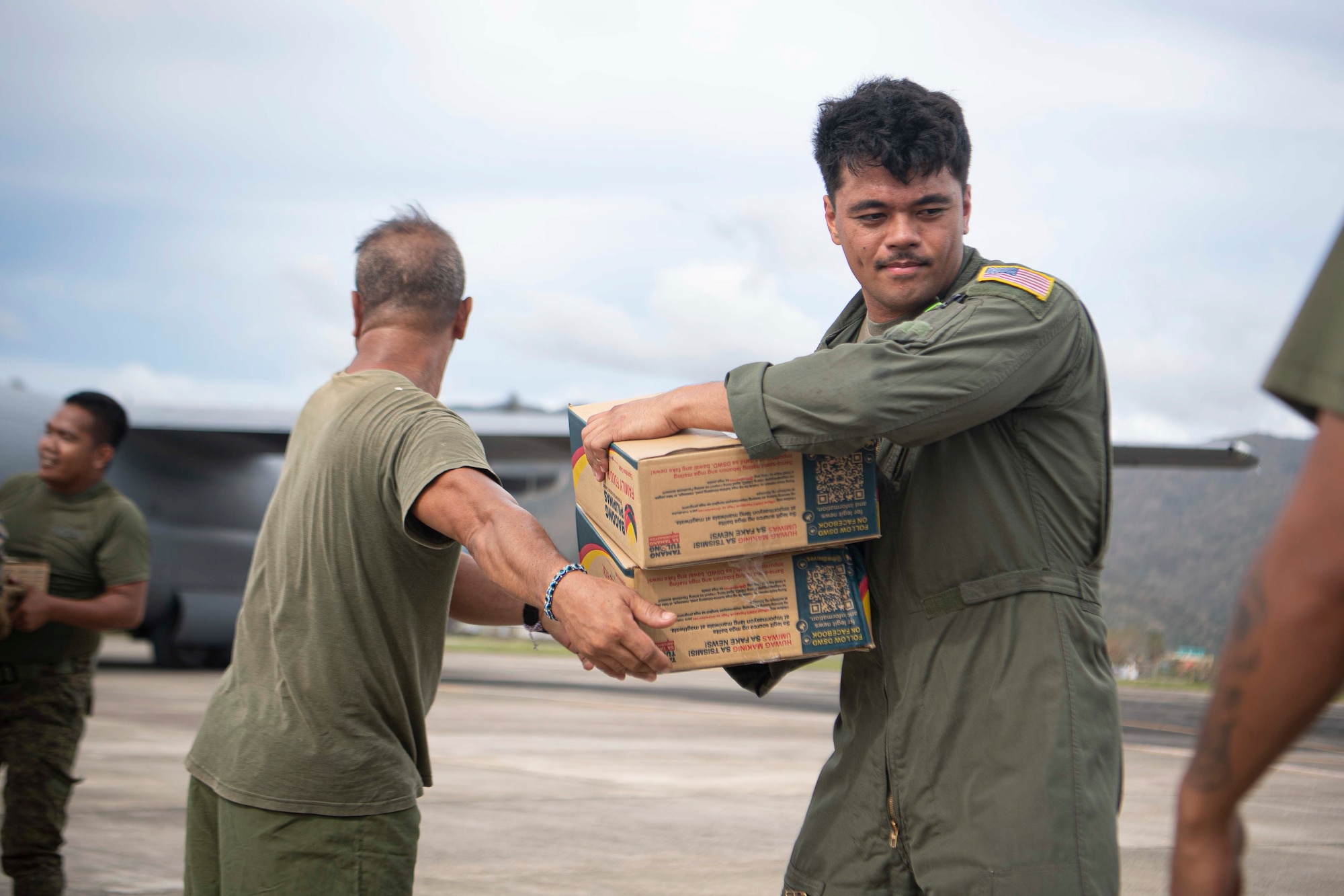 An Airman hands off family food packs during a foreign disaster relief operation.