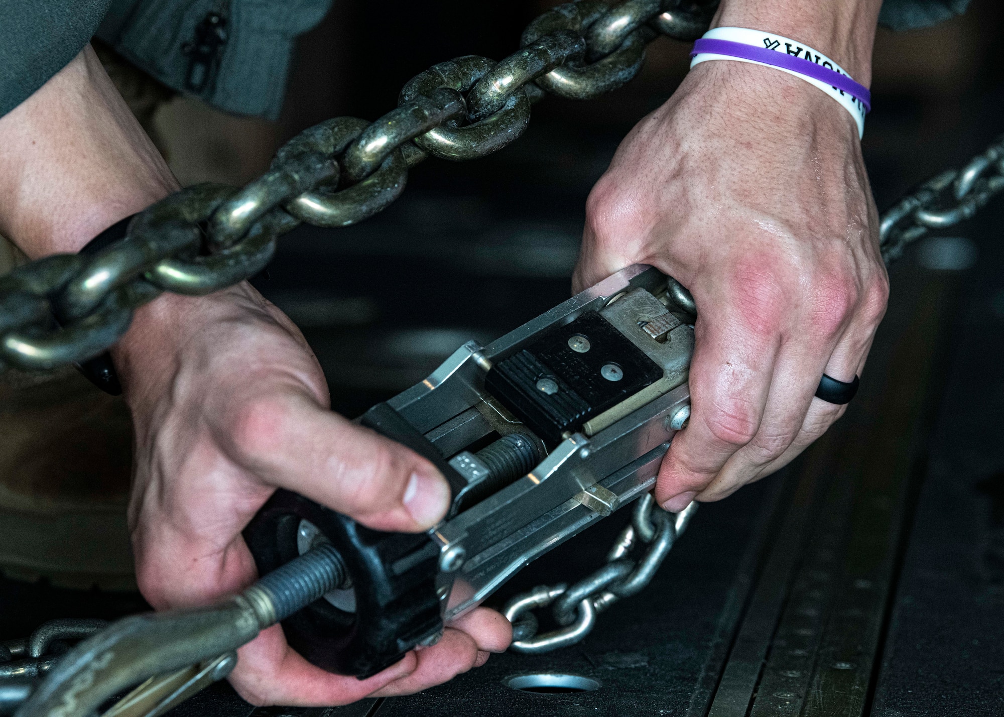 An Airman secures a cargo chain on a C-130J Super Hercules during a foreign disaster relief operation.