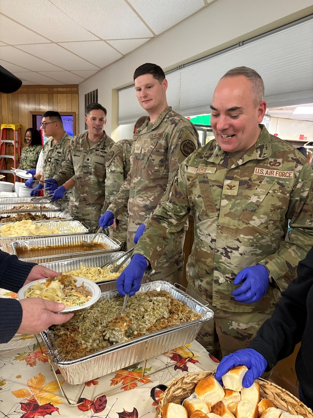Several men in military uniform, wearing blue gloves serving food