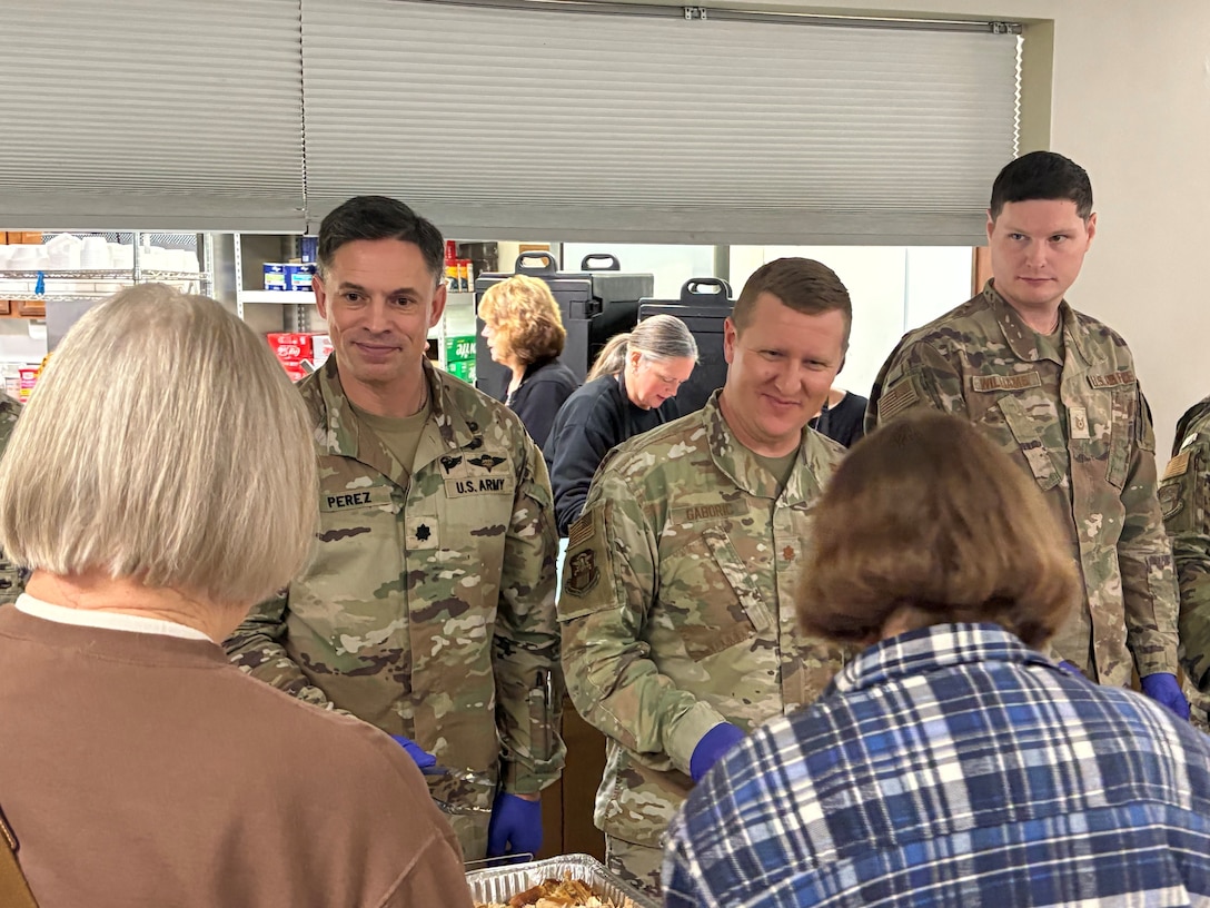 Three men in military uniform stand facing two women, both with neck-length hair.